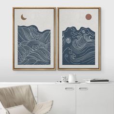 two framed art prints hanging on the wall above a white cabinet in a living room