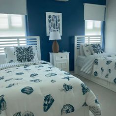 two beds in a room with blue walls and white furniture, one is made up to look like an ocean themed bed