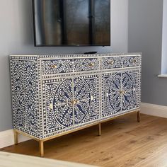 an ornate blue and white cabinet in front of a flat screen tv mounted on a wall