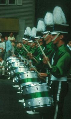 a group of men in green uniforms playing drums