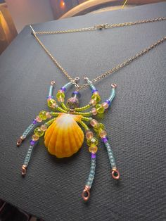 a close up of a necklace on a table with a sea shell and chain attached to it