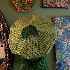 a green knitted hat sitting on top of a table next to pictures and mirrors