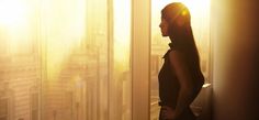 a woman standing in front of a window with the sun shining down on her head