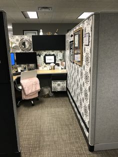 an office cubicle is decorated with black and white wallpaper, patterned walls, and carpeted flooring