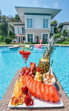 a large platter of fruit is on the edge of a swimming pool