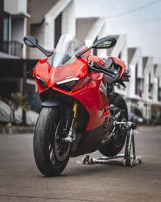 a red motorcycle parked in front of some houses