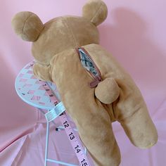 a teddy bear laying on top of a chair with a measuring tape around it's neck