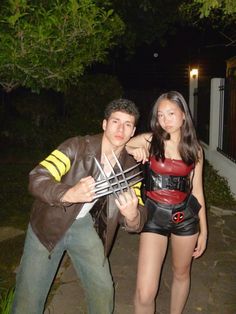 a man standing next to a woman holding a spider - man cosplay costume