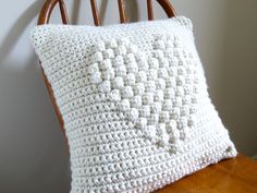 a white crocheted pillow sitting on top of a wooden chair