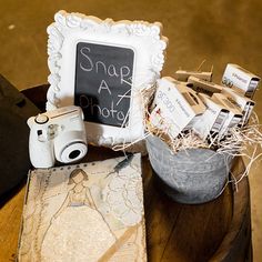 there is a small chalkboard on top of a barrel with other items in it