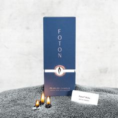 two candles sitting on top of a table next to a blue box that says footon