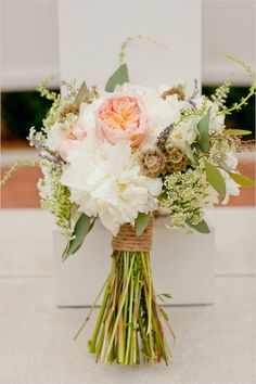 a bouquet of flowers sitting on top of a white box with greenery around it