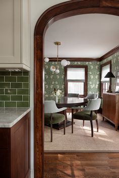 a dining room with green wallpaper and wood trim around the table, along with chairs