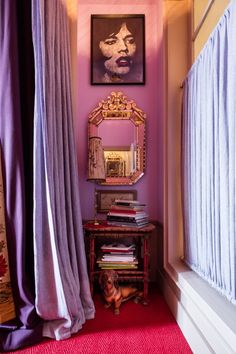 a pink room with curtains and a mirror on the wall next to a red rug