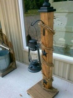 a wooden post with some lights attached to it in front of a window and a lantern