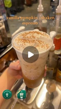 a person holding up a cup of coffee in front of a display case with the words vanilla pumpkin shaker espresso on it