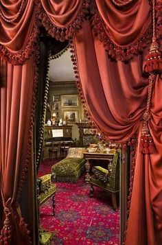 an ornately decorated living room with red curtains and pink carpeted area rugs