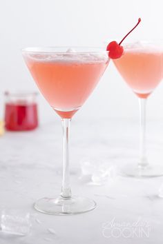 two glasses filled with pink liquid and a cherry garnish on the rims