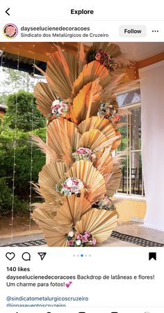 a tall vase with flowers on it sitting in front of a window next to a wall