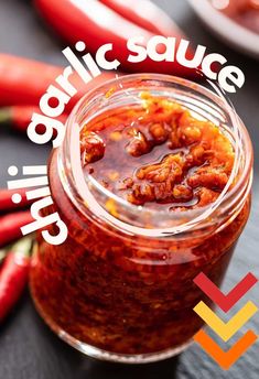 a jar filled with chili sauce sitting on top of a table next to red peppers