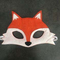 a red and white fox mask sitting on top of a black table next to a pair of scissors