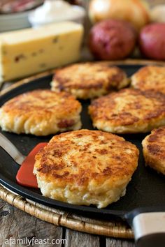 four crab cakes on a plate with cheese and apples in the background