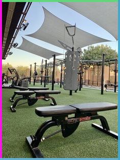 an outdoor gym area with benches and exercise equipment on artificial grass in the foreground