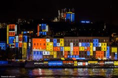 colorful buildings are lit up at night by the water