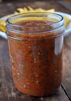 a jar filled with sauce sitting on top of a wooden table