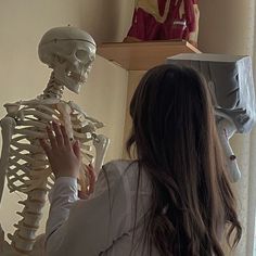 a woman standing in front of a skeleton