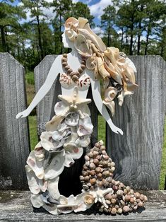 a statue made out of seashells sitting on top of a wooden fence