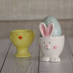 two ceramic easter eggs and a yellow egg cup