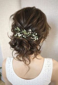 the back of a woman's head wearing a white top with flowers in her hair