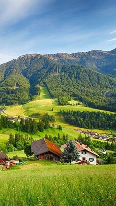 the mountains are covered with green grass and houses in the foreground, surrounded by lush greenery