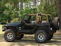 a black jeep with four wheels parked in the woods