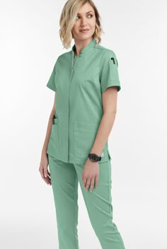 The UA Butter-soft Stretch women s 6-pocket collar neck zip front scrub top scrub top features a modern fit with a stand collar style and concealed zipper with top-button closure for a sleek appearance. There are 6 pockets total; 4 flattering angled roomy front pockets and 2 pen pockets on wearers left sleeve for easy access. It has a three piece back panel for fit and comfort, as well as side vents for ease of movement. Fabric is made up of 55 42 3 cotton poly spandex. • Modern fit • Stand Coll Nurses Uniform Modern, Scrubs Aesthetic, Scrub Skirts, Scrub Undershirts Long Sleeve, Long Sleeve Scrubs Uniform, Yoga Scrub Pants, Teal Scrub Pants, Surgical Green Scrubs, Medical Scrubs Fashion