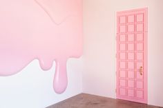 a pink door is in the corner of a room with a painting on the wall