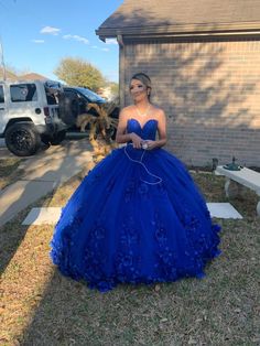 a woman in a blue ball gown standing on the side of a road next to a house