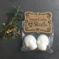 two sugar cubes sitting on top of a bag next to some flowers and leaves