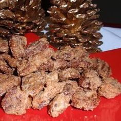 pine cones are piled on top of each other in front of a red plate with gold sequins