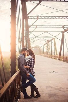 a man and woman kissing on a bridge