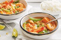 two bowls filled with shrimp and vegetables next to rice on a white tablecloth,