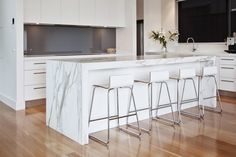 a kitchen with marble counter tops and stools next to an island in the middle