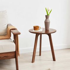 two chairs and a table with a vase on it in front of a white wall