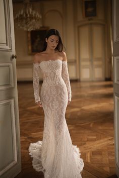 a woman in a white wedding dress is standing near an open door and looking down at the floor