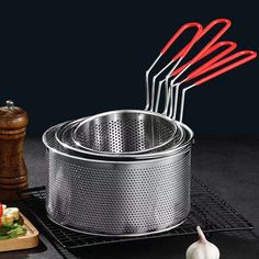 a bunch of red handled utensils sitting on top of a metal pan next to a cutting board