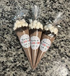 three cones filled with white chocolate and marshmallows on top of a granite counter