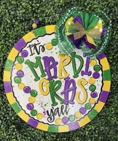 a mardi gras sign on top of a green grass covered ground with decorations