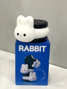 a white and black toy sitting on top of a blue box with the word rabbit in it