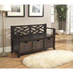 a wooden bench with baskets underneath it on the floor next to a rug and framed pictures